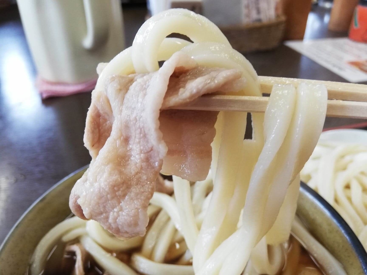 川越『藤店うどん』の肉汁うどんをスープにつけた写真