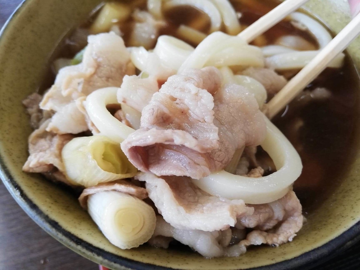 川越『藤店うどん』の肉汁うどんをスープにつけた写真
