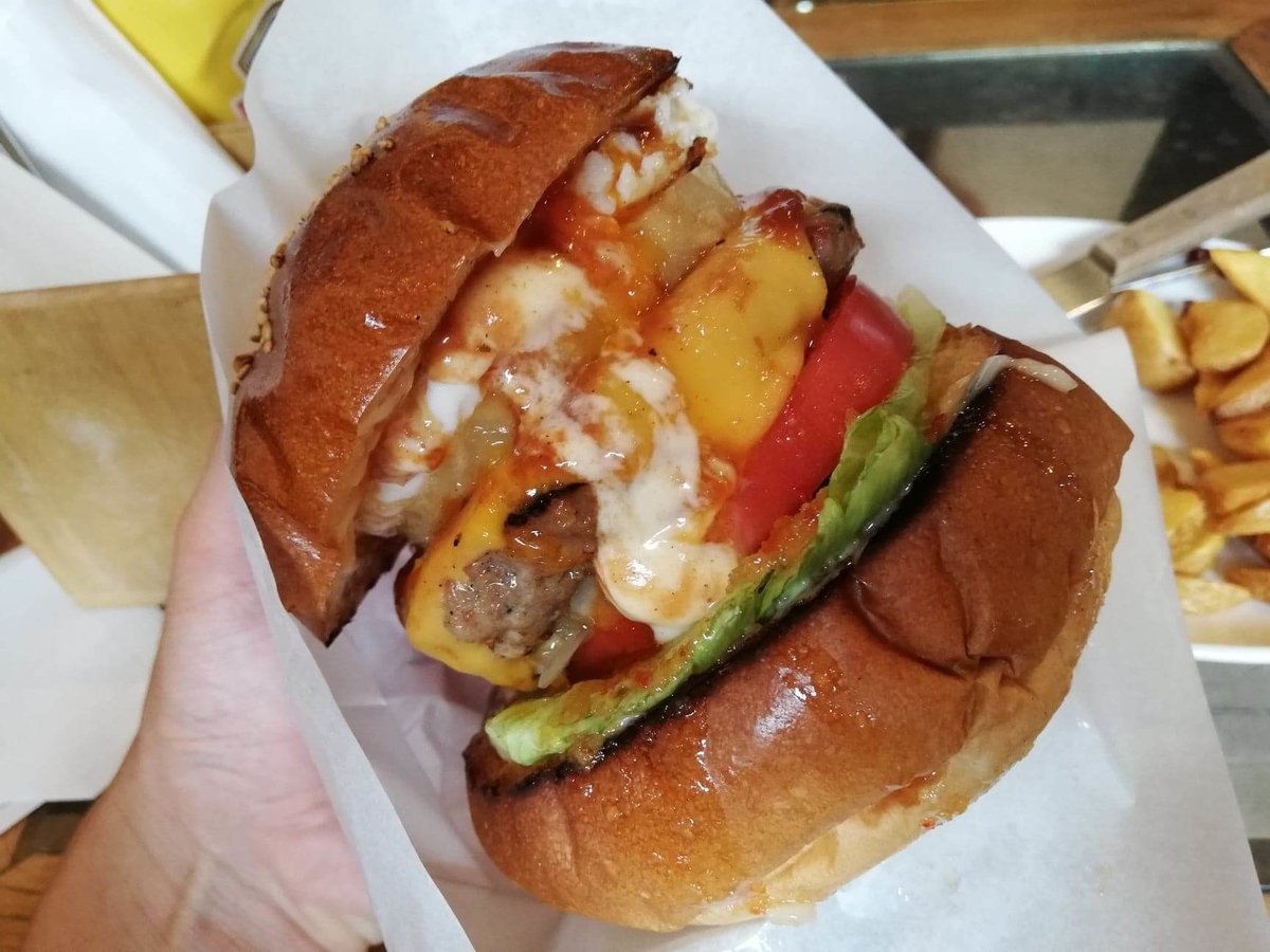 本川越『バーガーカフェホノホノ（BurgerCafe honohono）』のホノホノバーガーを手で持ち上げた写真