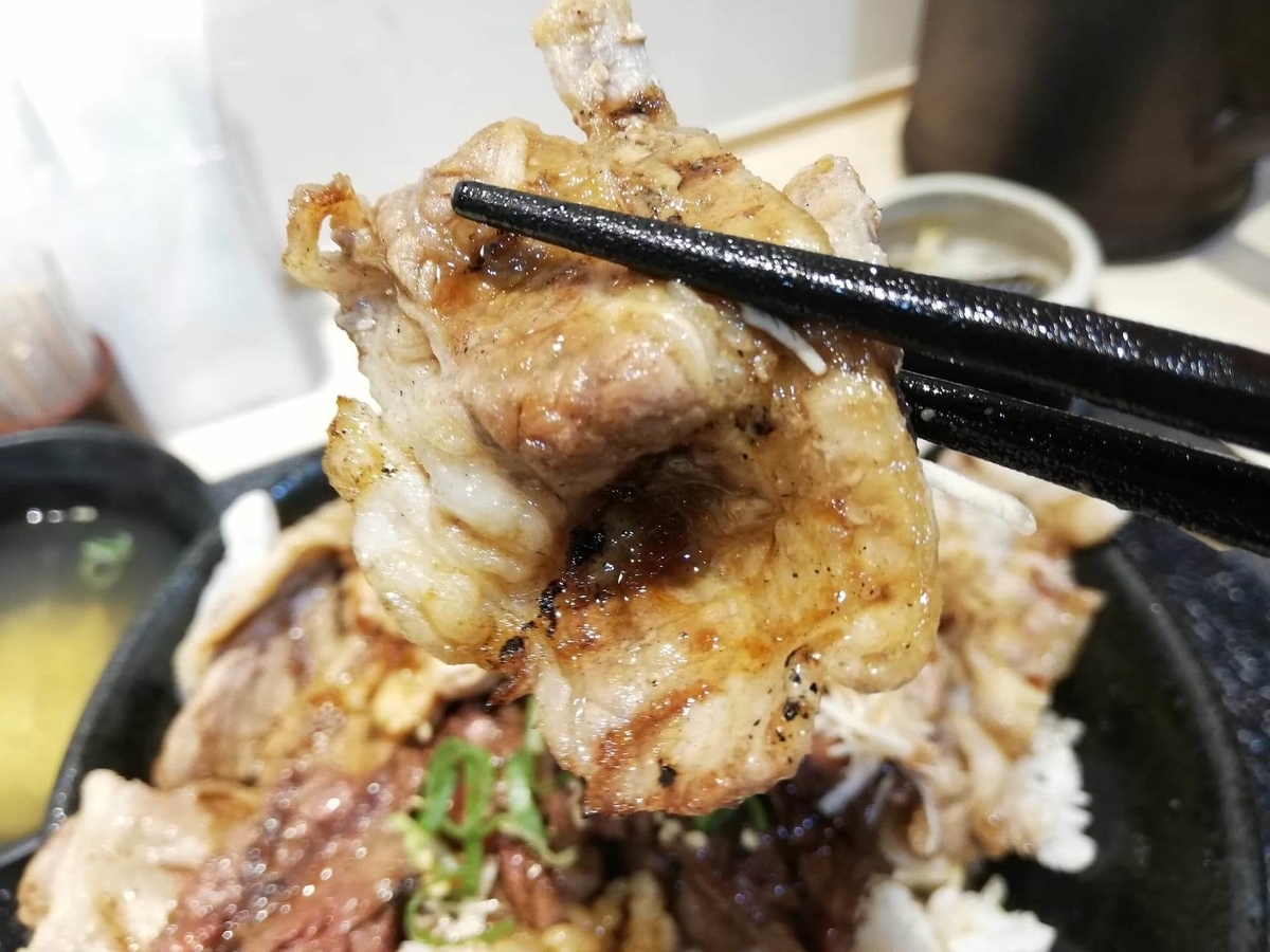 池袋『肉劇場』の大劇場丼の肉を箸で掴んでいる写真