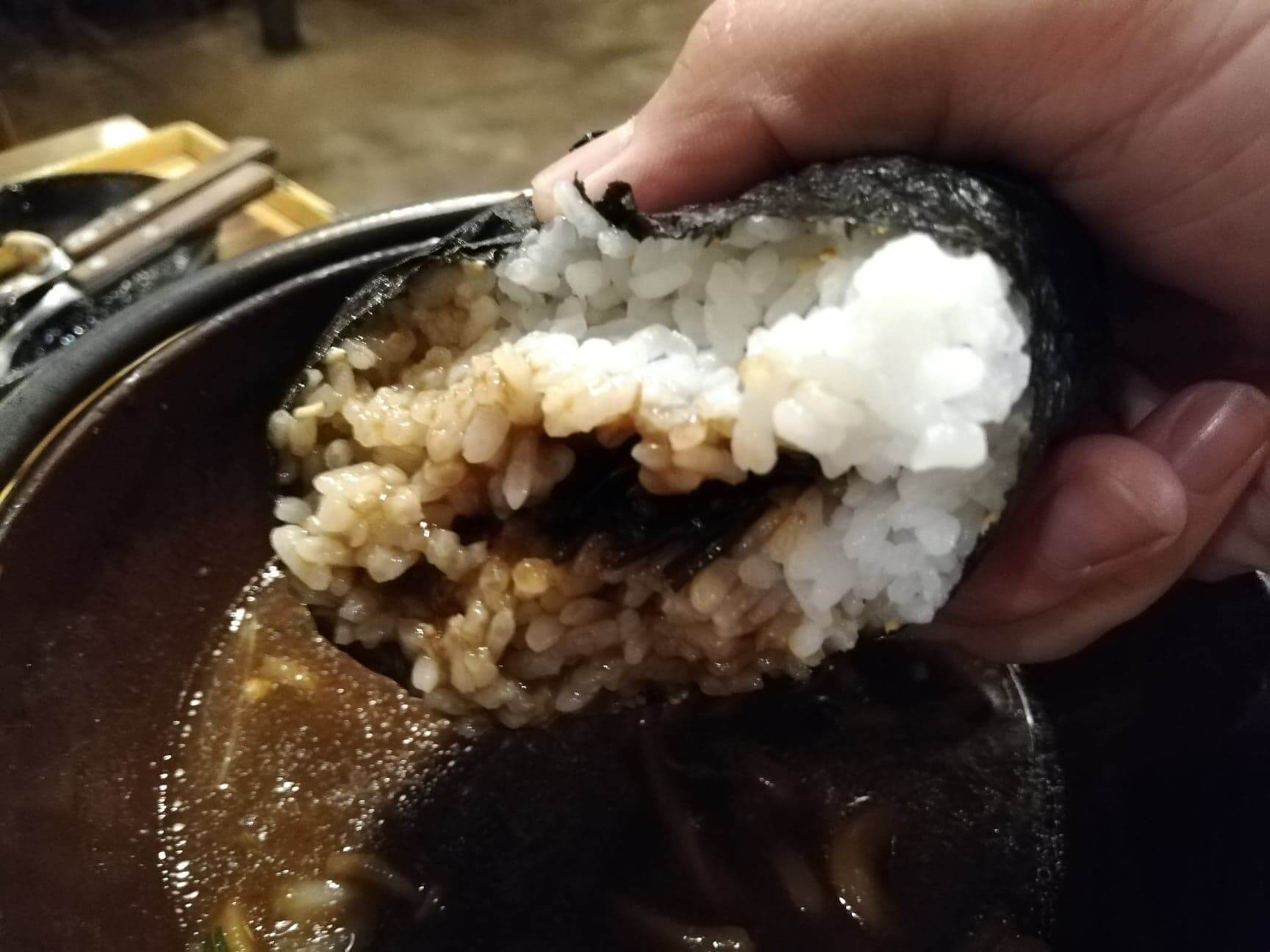 広島県の前空駅『田舎茶屋わたや大野店』の山賊むすびをスープにつけている写真