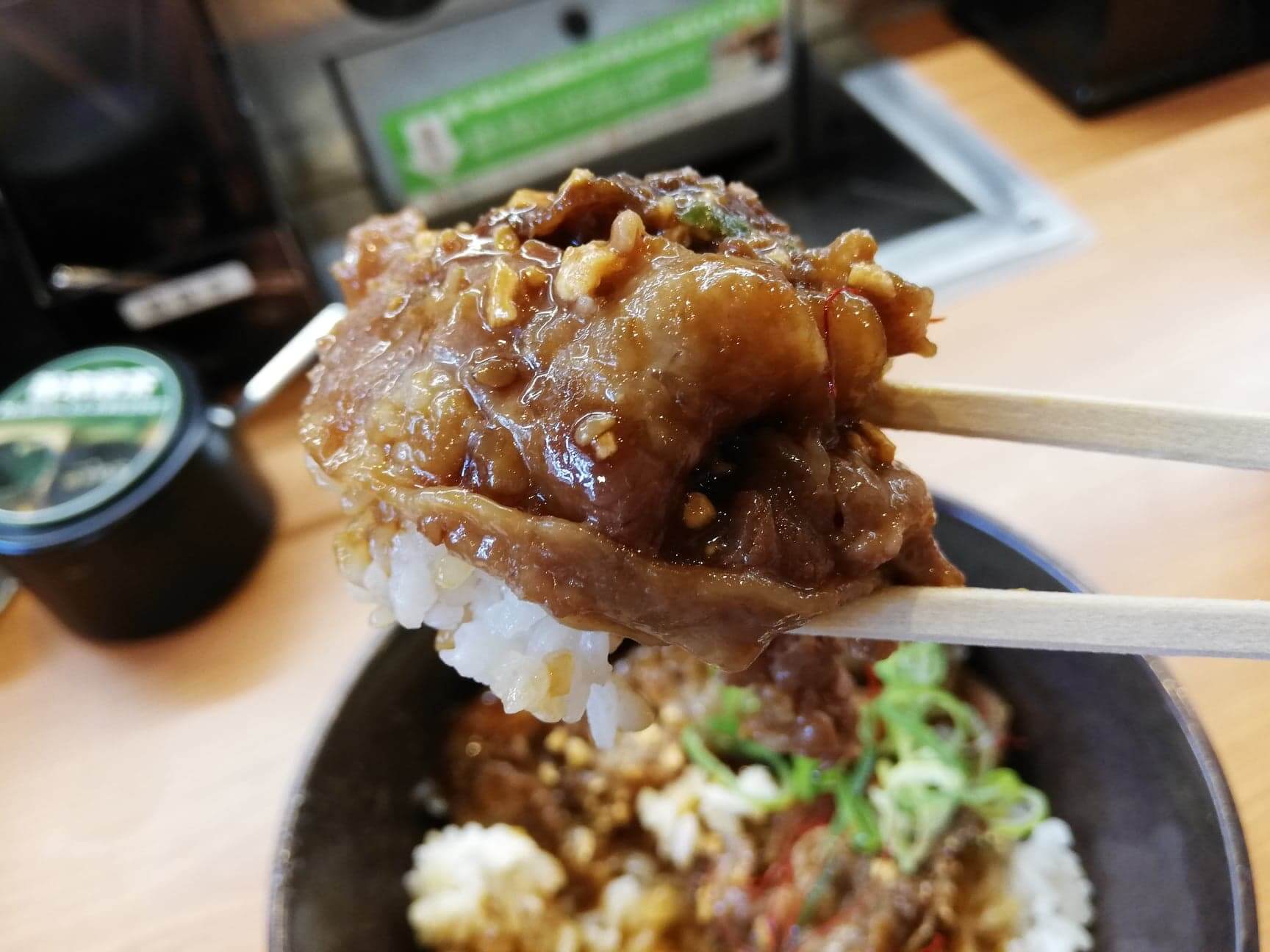 くら寿司の平日限定ランチ『牛カルビ丼ガーリック』を箸で掴んでいる写真