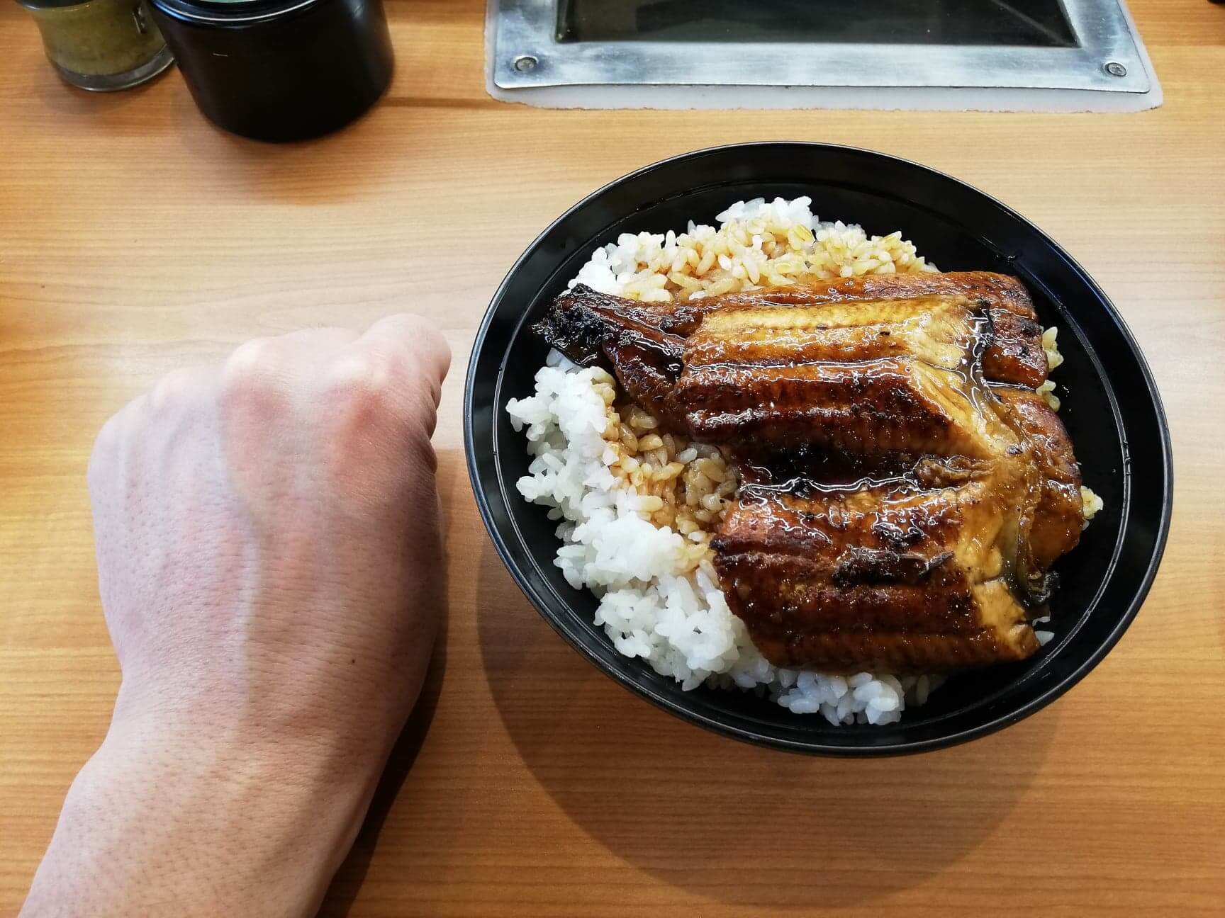 くら寿司の平日限定ランチ『特上うな丼ランチ』と拳のサイズ比較写真