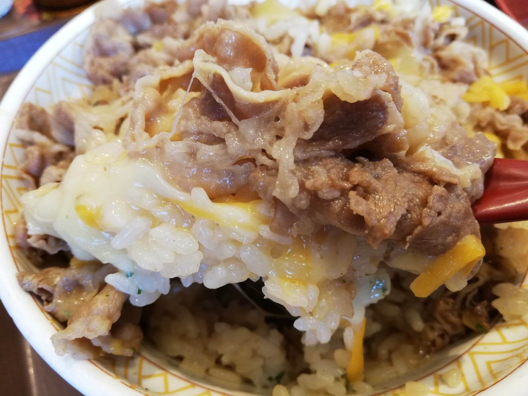 すき家の『とろーり3種のチーズ牛丼』をレンゲで持ち上げた写真