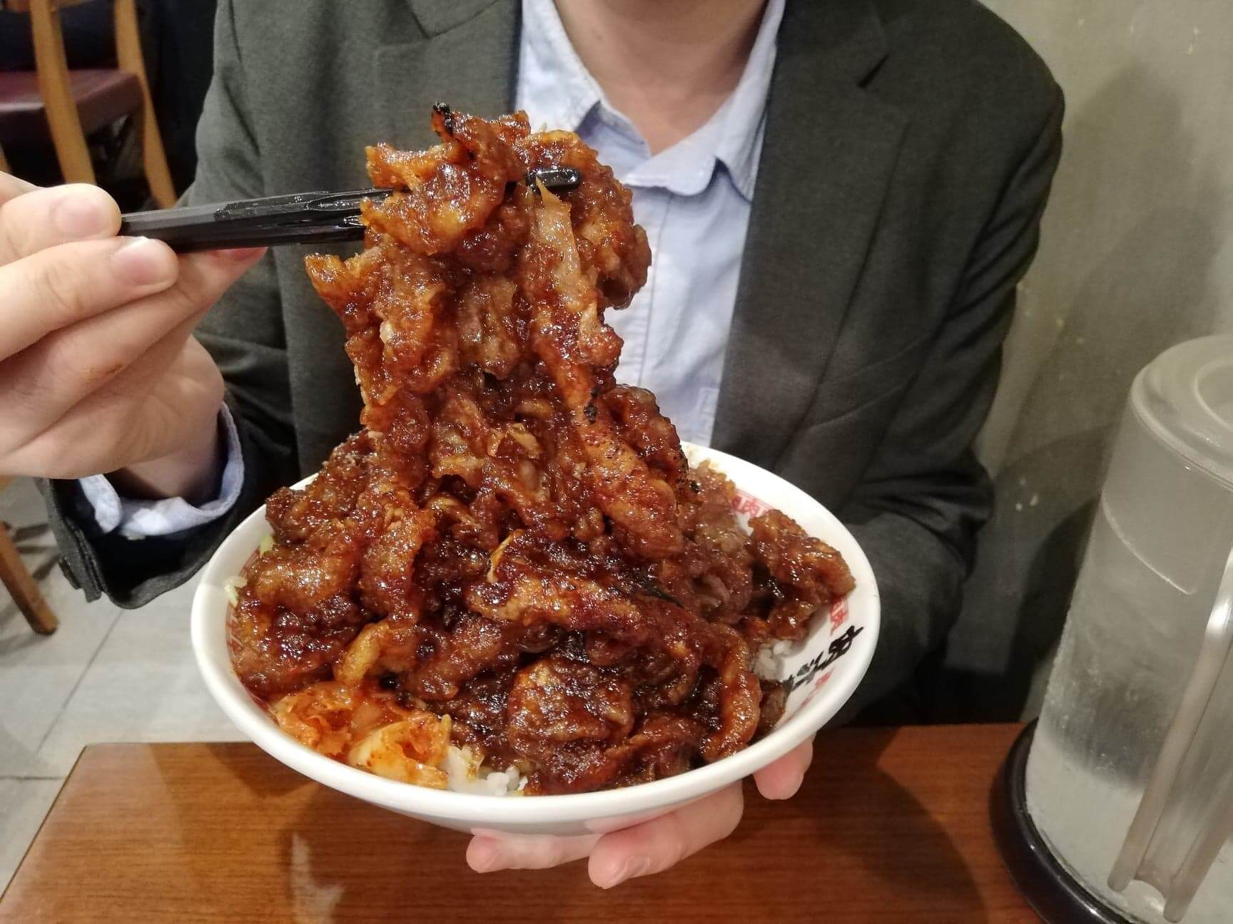 高田馬場『肉汁麺ススム』の肉汁丼を箸で持ち上げている写真