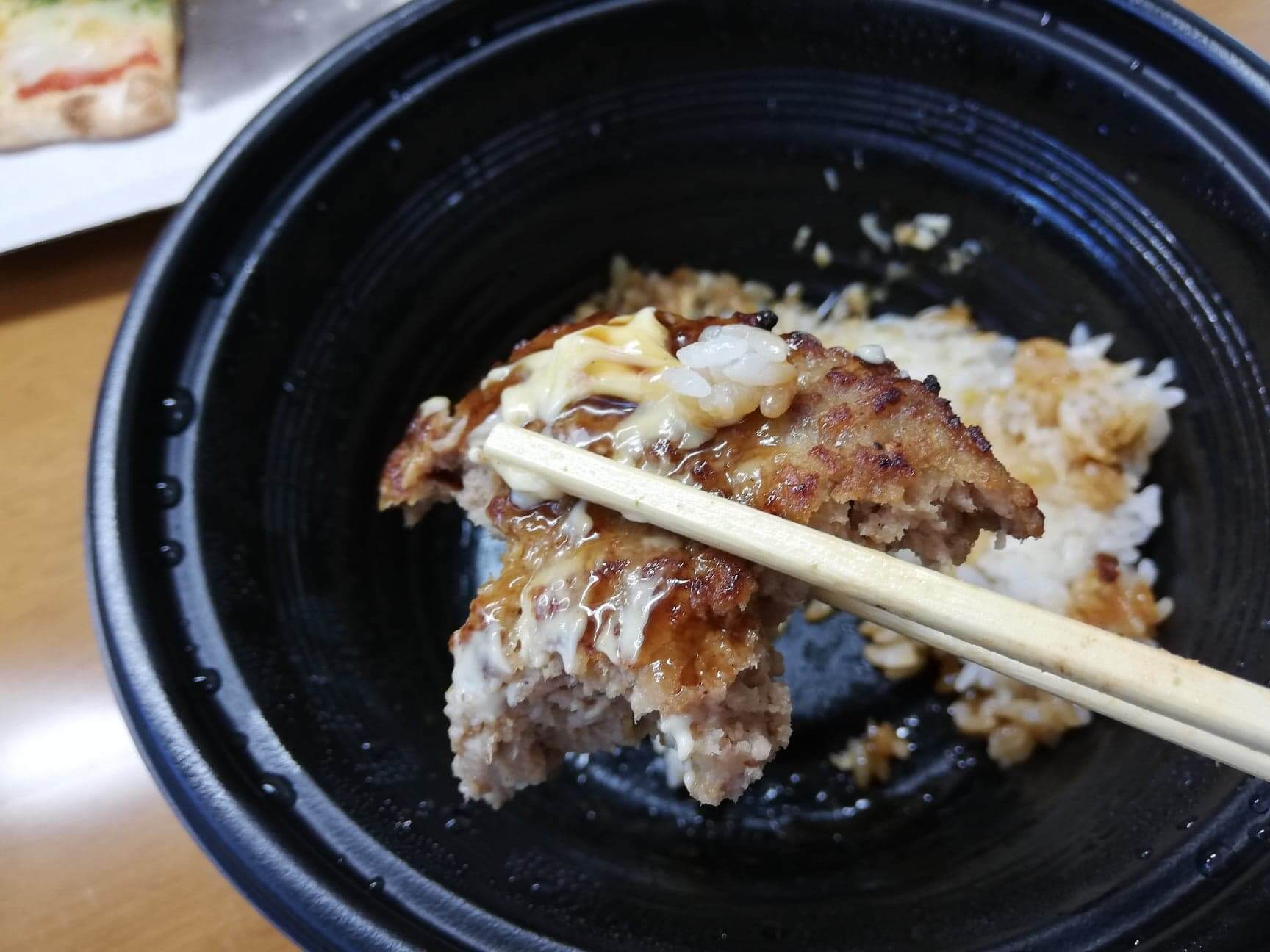 ガストのテイクアウトメニュー『ランチハンバーグロコモコ丼』のハンバーグを箸で持ち上げた写真