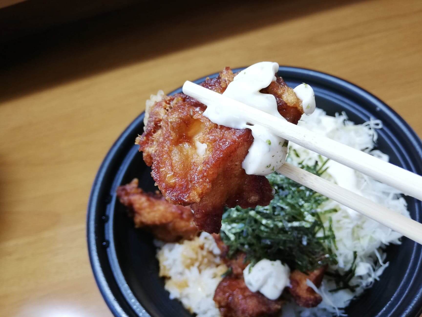 ガストのテイクアウトメニュー『ランチ唐揚げテリタル丼』の唐揚げを箸で持ち上げた写真
