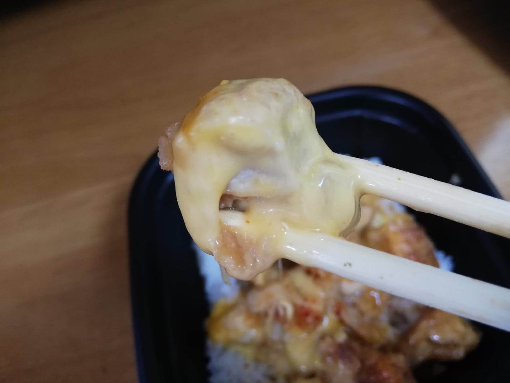 ファミマの『とろーりチーズの唐揚丼』の唐揚げを箸で持ち上げている写真